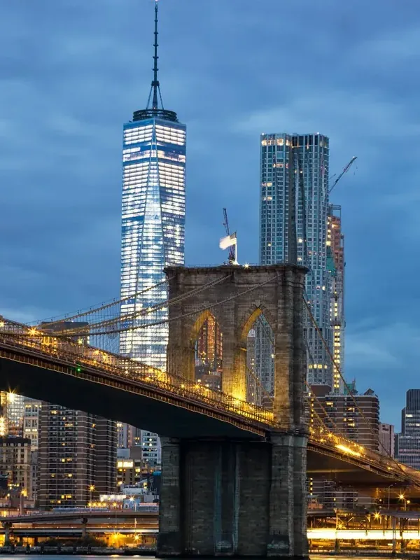 Le pont de Brooklyn éclairé, devant les tours de Manhattan à la tombée du jour.