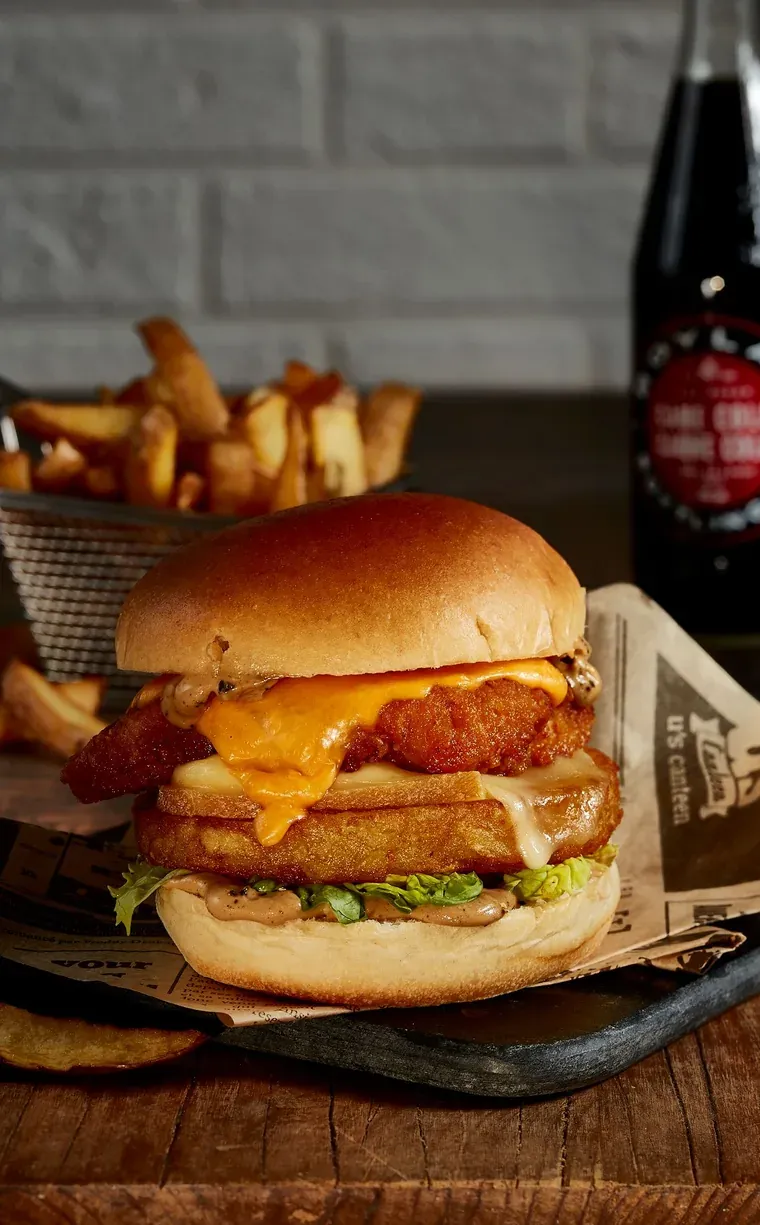 Burger au poulet pané posé sur une galette de pomme de terre dorée