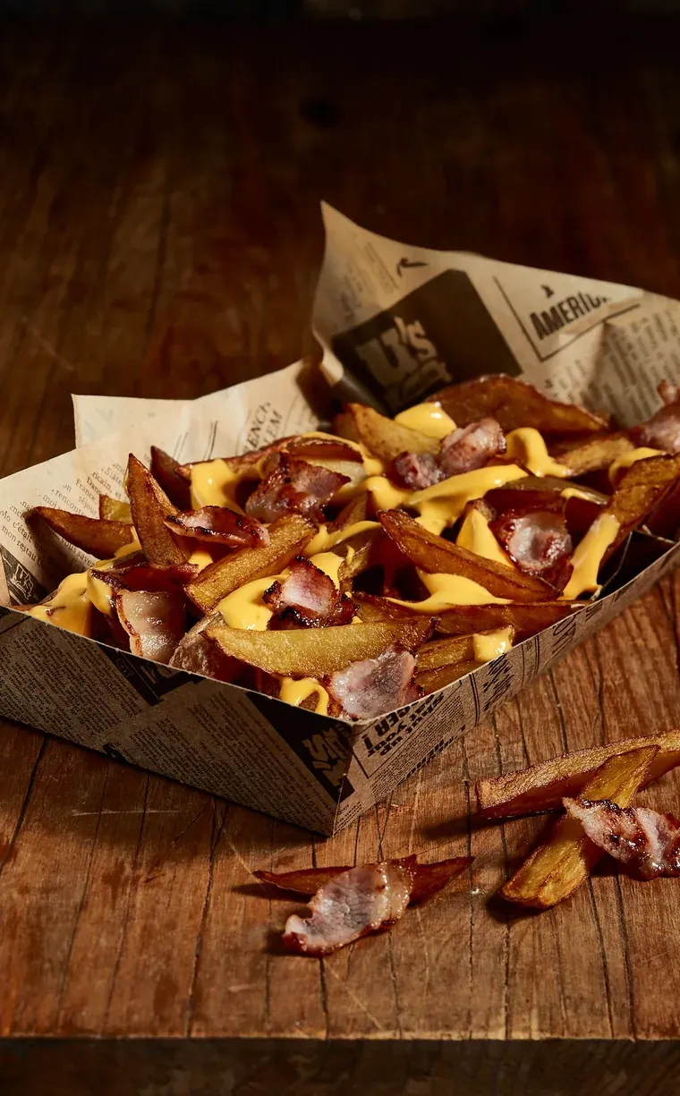 Barquette de frites maison nappées de cheddar fondu et de lardons grillés
