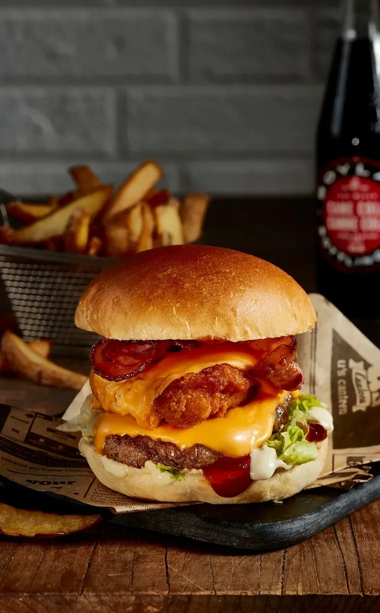Burger au cheddar, poulet pané et bacon grillé, servi avec des frites