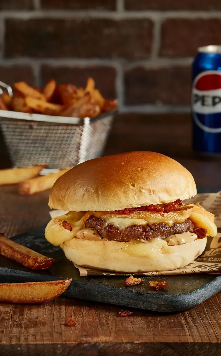 Burger au steak et à la raclette fondante, servi avec des frites maison