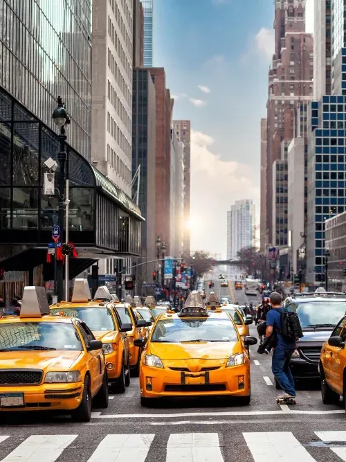 File de taxis jaunes à un passage piéton, avenue de Manhattan en enfilade.