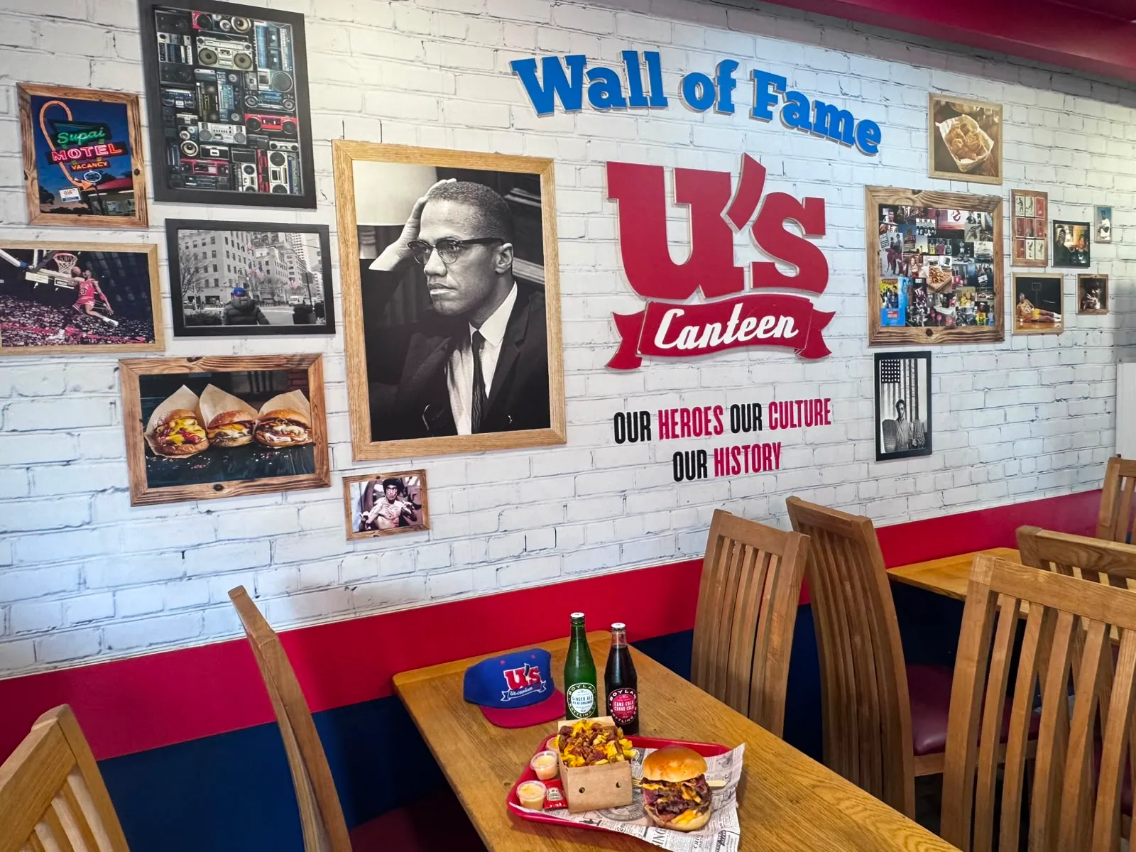Mur de briques blanches couvert de cadres, le « Wall of Fame » d'une salle U's Canteen.